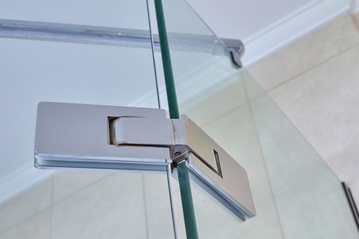 Stainless steel hinge on a safety-glass shower enclosure